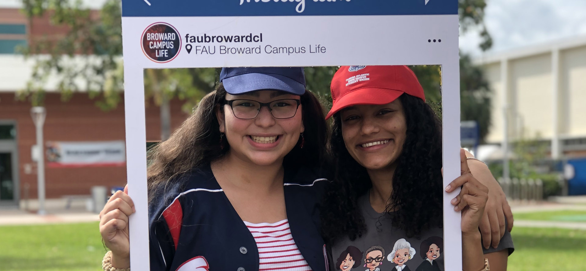 Two students taking a picture with a instagram post cutout