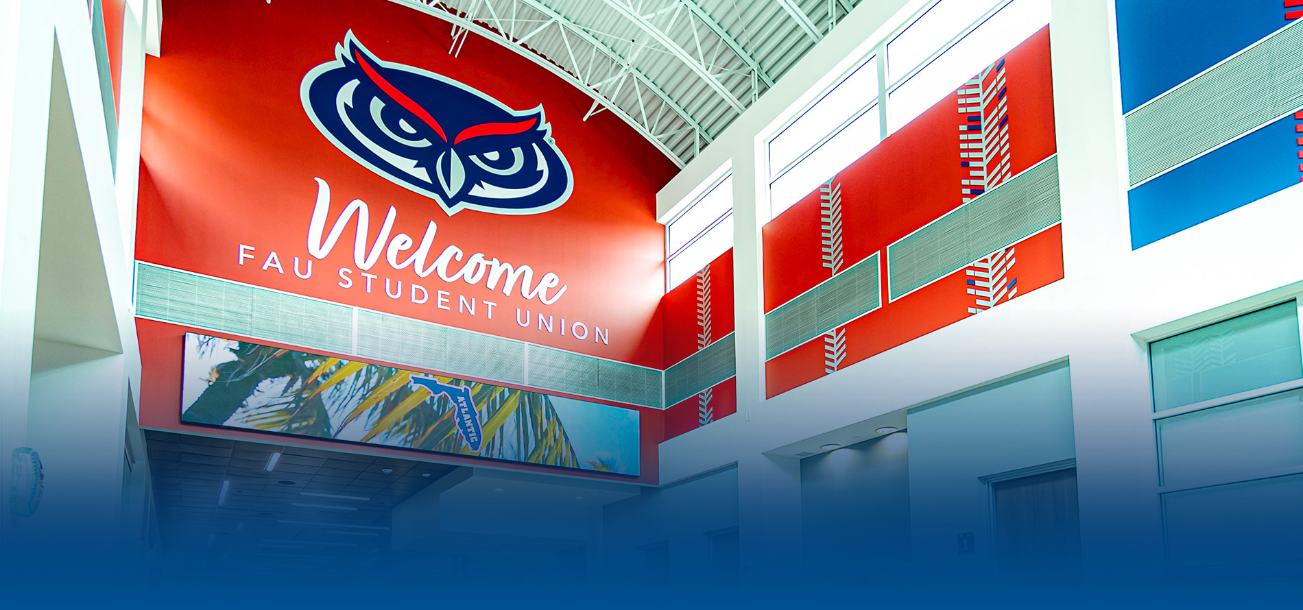 Interior view of FAU Student Union with an owl logo and welcome message on a red wall.