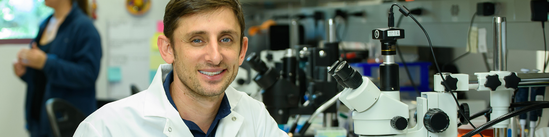Professor in lab coat smiling at camera