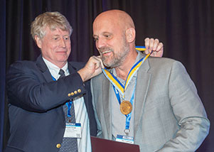 Dr. Stewart Glegg putting medal around Professor Tim Colonius's neck