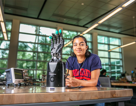 FAU student in front of a robotic hand