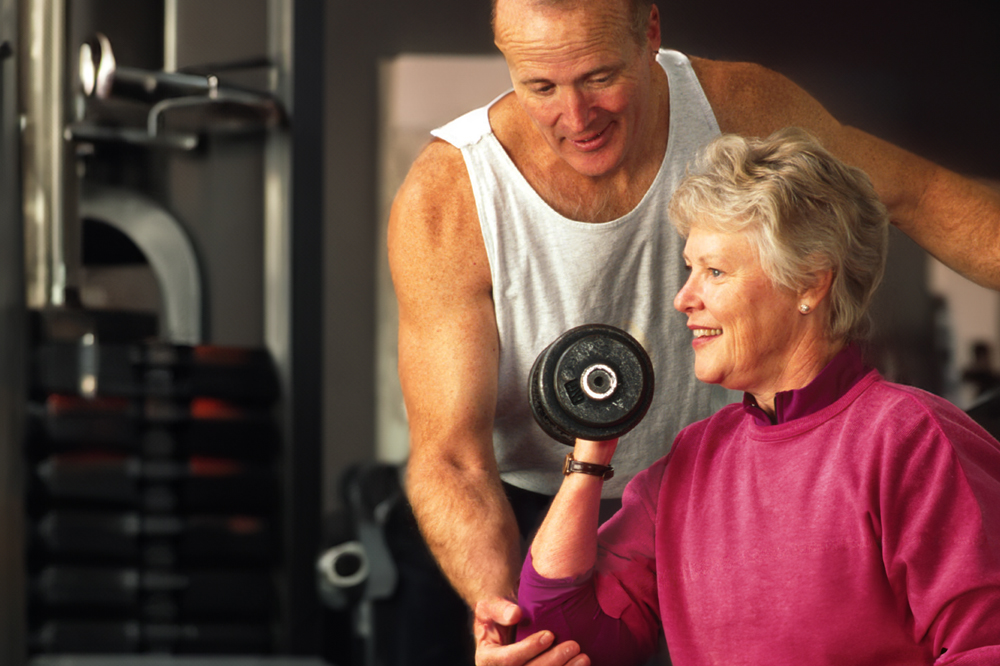 Trainer helping an elderly woman with a workout