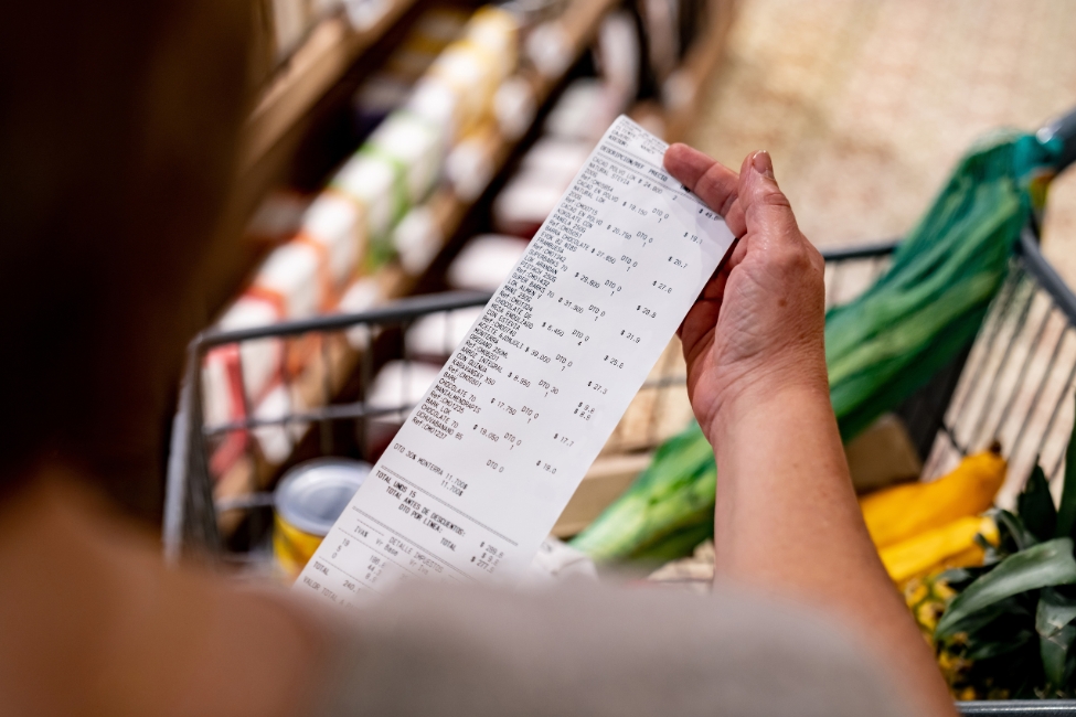 A close up of a hand holding a grocery receipt 