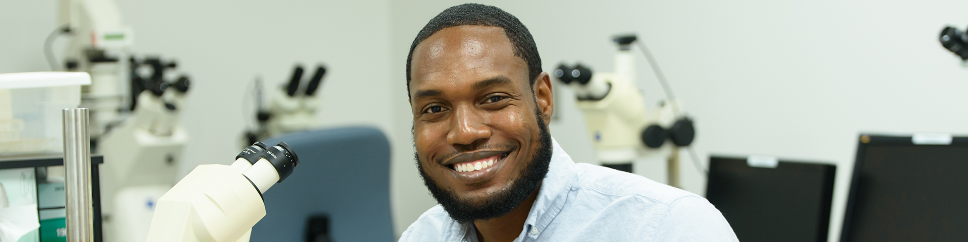 Post doc looking up from microscope and smiling