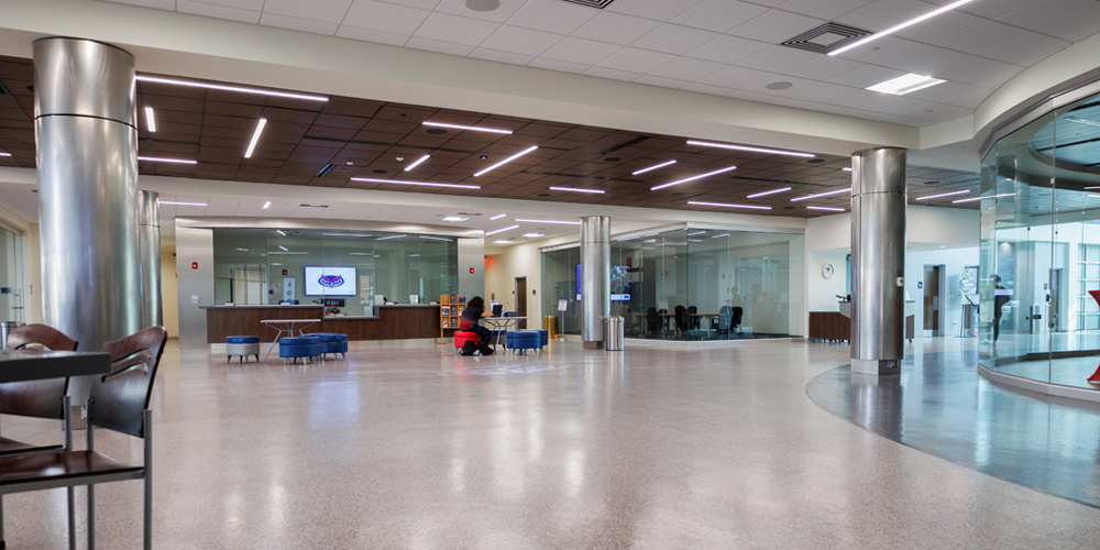 Spacious student union lobby with seating areas, metal columns, glass-walled rooms, and the box office in the background