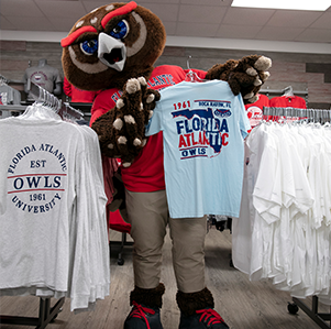 FAU mascot, Owlsley, holding up an FAU shirt in the bookstore