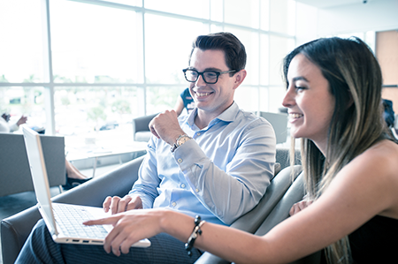 Male and female student looking at a laptop smiling