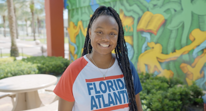 Student standing smiling against a graffiti wall art